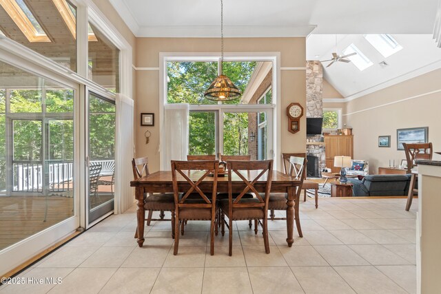 tiled dining space with ornamental molding, ceiling fan, high vaulted ceiling, and a skylight