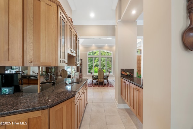 kitchen featuring light tile patterned flooring, sink, crown molding, and dark stone counters