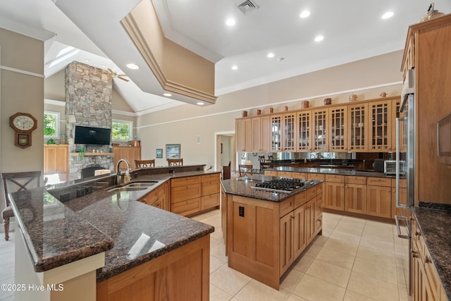 kitchen featuring a fireplace, sink, ornamental molding, a large island, and kitchen peninsula