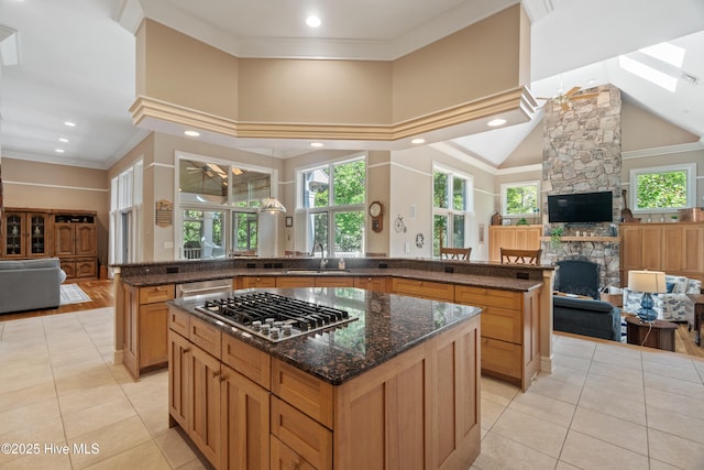 kitchen featuring a fireplace, dark stone counters, a center island, kitchen peninsula, and stainless steel appliances