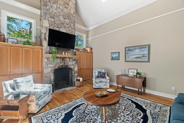 living room with hardwood / wood-style floors, a fireplace, ornamental molding, and high vaulted ceiling