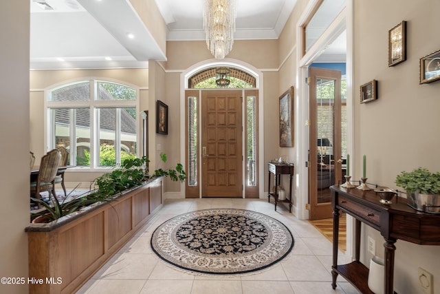 tiled foyer with an inviting chandelier and crown molding