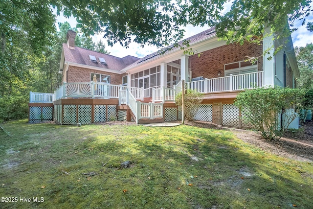 rear view of house featuring a wooden deck, a sunroom, and a yard