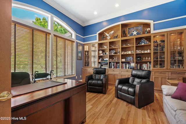 office area with crown molding, a healthy amount of sunlight, and light wood-type flooring