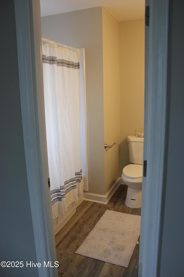 bathroom featuring hardwood / wood-style floors, a shower with curtain, and toilet