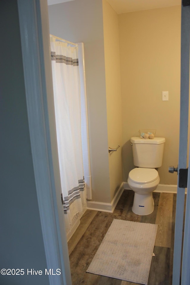 bathroom featuring hardwood / wood-style floors, curtained shower, and toilet