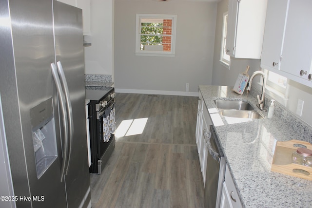 kitchen with stainless steel appliances, sink, white cabinets, and light stone counters