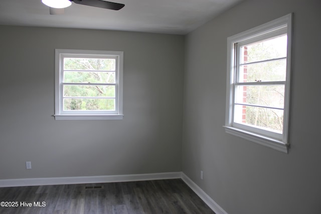 empty room with dark wood-type flooring, a wealth of natural light, and ceiling fan