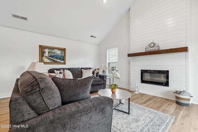 living room featuring high vaulted ceiling and light hardwood / wood-style flooring