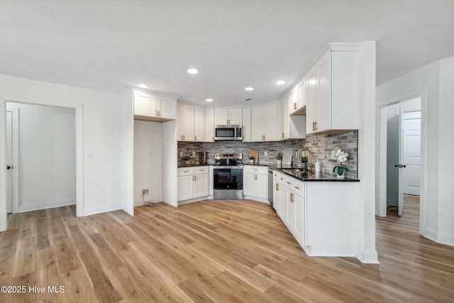 kitchen with appliances with stainless steel finishes, light hardwood / wood-style flooring, decorative backsplash, and white cabinets