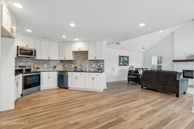 kitchen with white cabinetry, light wood-type flooring, tasteful backsplash, and appliances with stainless steel finishes