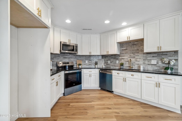 kitchen with tasteful backsplash, sink, white cabinets, light hardwood / wood-style floors, and stainless steel appliances