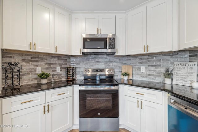 kitchen with dark stone countertops, tasteful backsplash, stainless steel appliances, and white cabinets