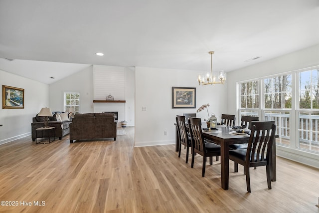 dining space with vaulted ceiling, light hardwood / wood-style flooring, and a notable chandelier