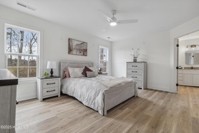 bedroom featuring ceiling fan, sink, light hardwood / wood-style floors, and ensuite bath