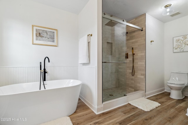 bathroom featuring hardwood / wood-style flooring, shower with separate bathtub, and toilet