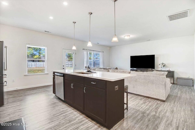 kitchen with sink, light hardwood / wood-style flooring, a kitchen island with sink, stainless steel appliances, and decorative light fixtures