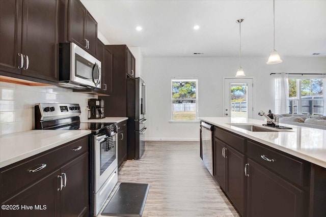 kitchen with pendant lighting, sink, plenty of natural light, stainless steel appliances, and decorative backsplash