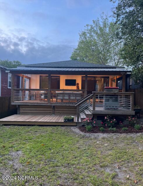 rear view of house with a wooden deck and a yard