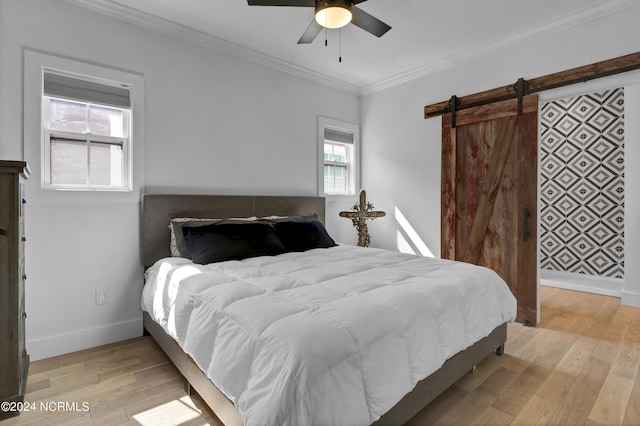 bedroom with ornamental molding, a barn door, ceiling fan, and light wood-type flooring