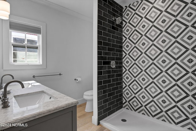 bathroom with a tile shower, vanity, hardwood / wood-style flooring, and toilet