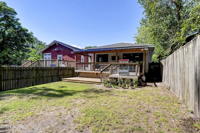 rear view of house with a wooden deck and a lawn