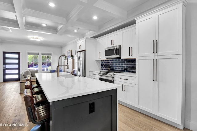 kitchen with a kitchen island with sink, white cabinets, and appliances with stainless steel finishes