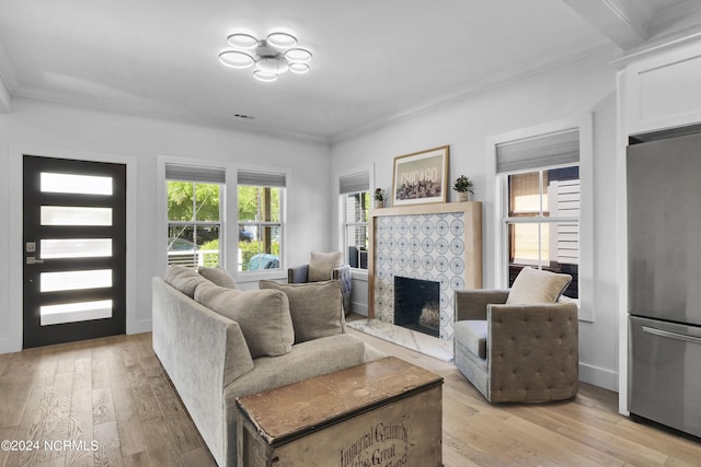 living room with crown molding, a fireplace, and light hardwood / wood-style flooring