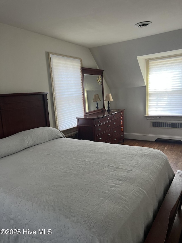 bedroom with lofted ceiling, hardwood / wood-style floors, and radiator