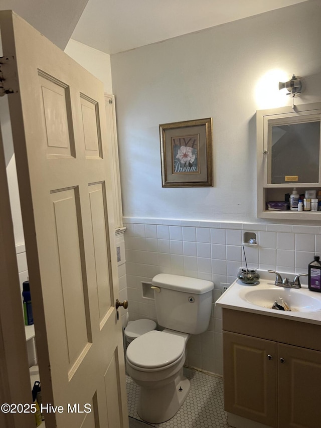 bathroom featuring vanity, tile patterned floors, toilet, and tile walls