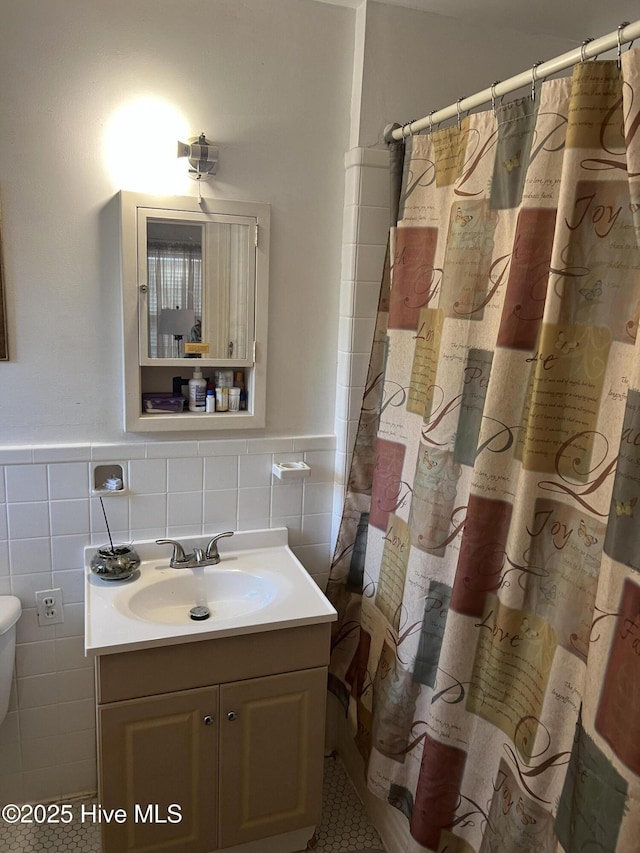 bathroom with vanity, a shower with shower curtain, and tile walls