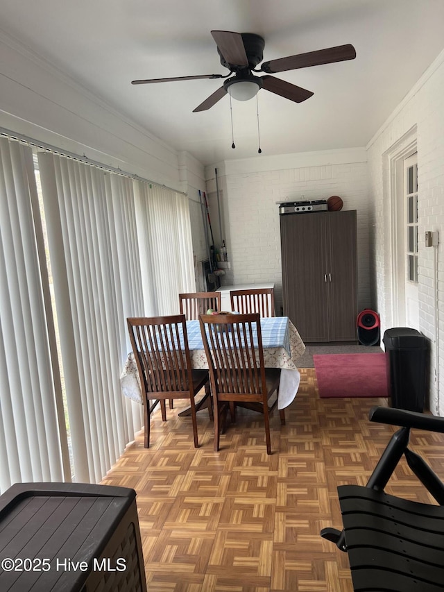 dining space featuring light parquet floors, brick wall, and ceiling fan