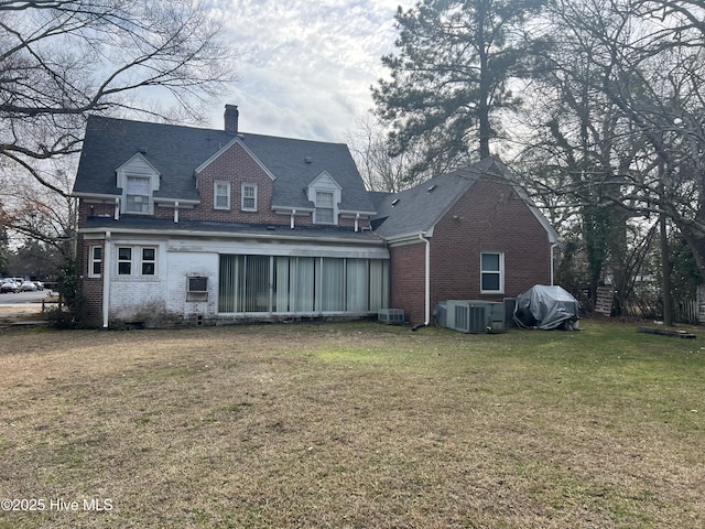 rear view of house with central AC and a lawn