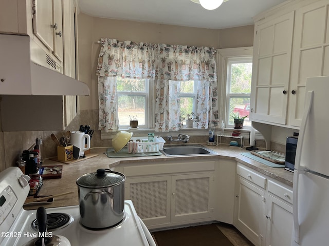 kitchen with white refrigerator, white cabinetry, sink, and electric range oven