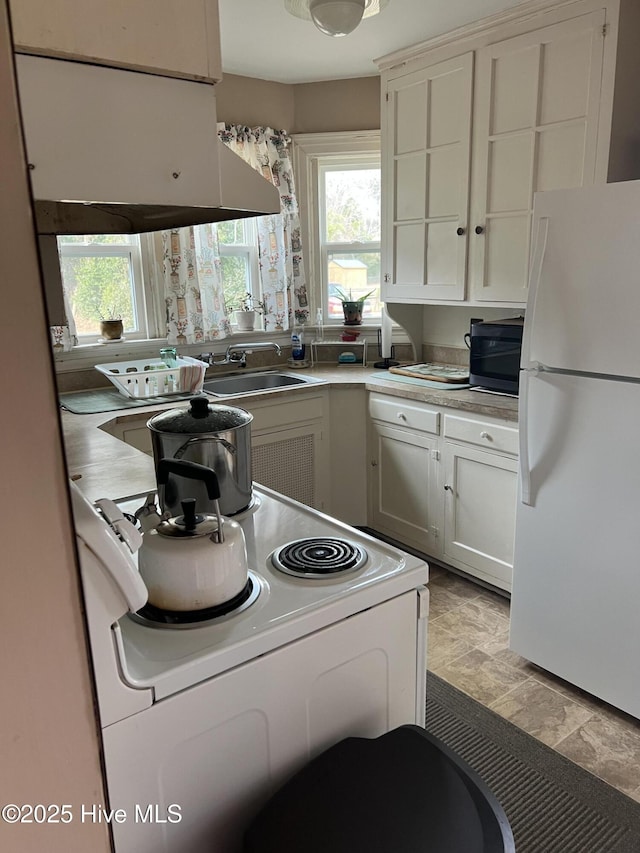 kitchen with white appliances, a healthy amount of sunlight, sink, and white cabinets