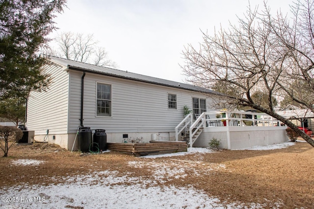 snow covered rear of property with a wooden deck and central AC unit