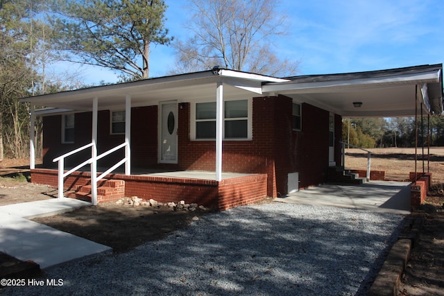 manufactured / mobile home featuring brick siding, a porch, and an attached carport