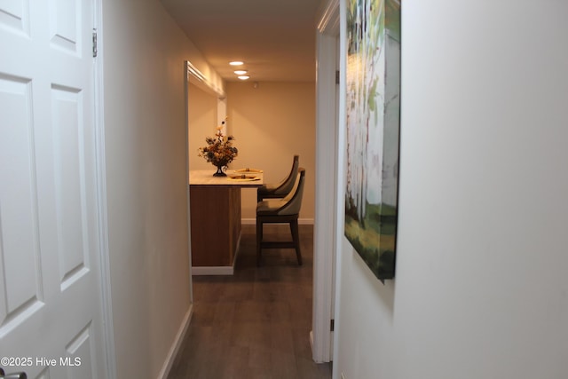 hallway featuring dark wood-style flooring, baseboards, and recessed lighting