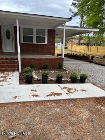 exterior space featuring an attached carport, a porch, and brick siding