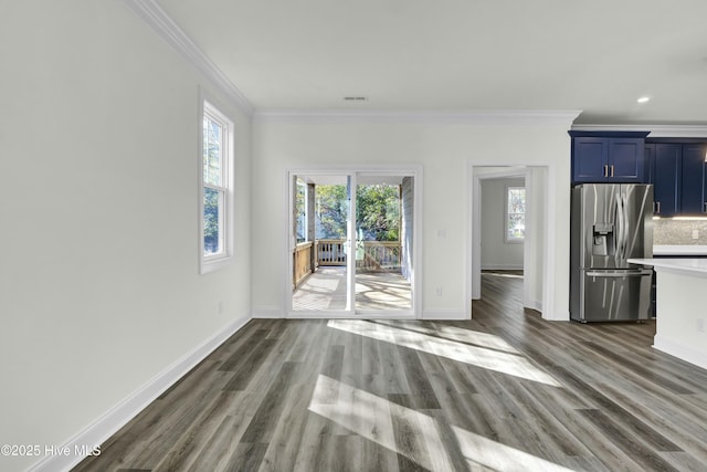 unfurnished living room with dark wood-type flooring, a healthy amount of sunlight, and ornamental molding