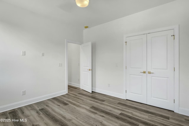 unfurnished bedroom with a closet, baseboards, and wood finished floors