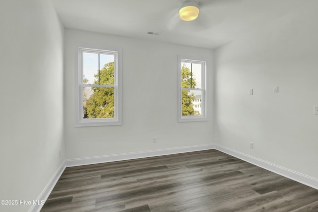 empty room with baseboards, plenty of natural light, dark wood-type flooring, and visible vents