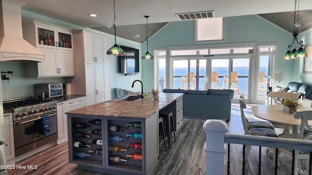 kitchen featuring high end stove, white cabinetry, dark stone counters, custom exhaust hood, and a water view