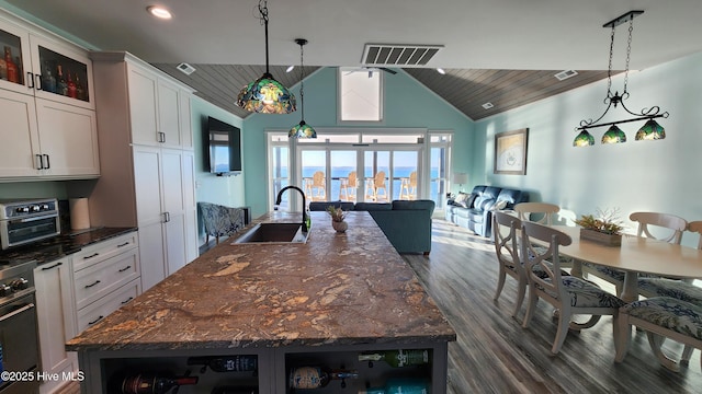 kitchen featuring sink, decorative light fixtures, dark stone counters, a large island, and white cabinets