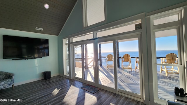 doorway with high vaulted ceiling, dark hardwood / wood-style floors, and a water view