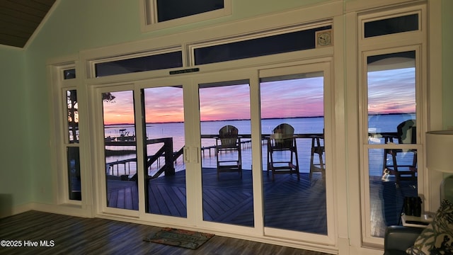 doorway to outside with lofted ceiling, dark wood-type flooring, and a water view