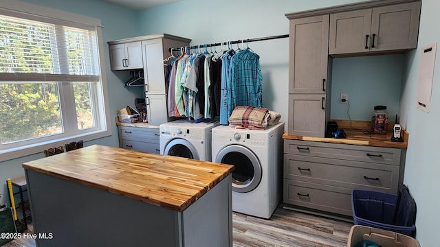 clothes washing area featuring cabinets, separate washer and dryer, and light hardwood / wood-style floors