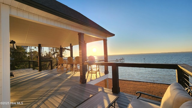 deck at dusk featuring a water view