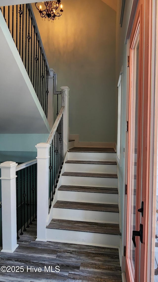 stairs featuring a notable chandelier and wood-type flooring