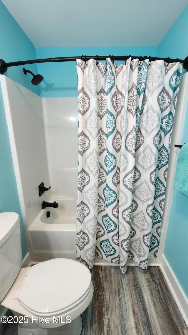 bathroom with shower / tub combo with curtain, hardwood / wood-style flooring, and toilet